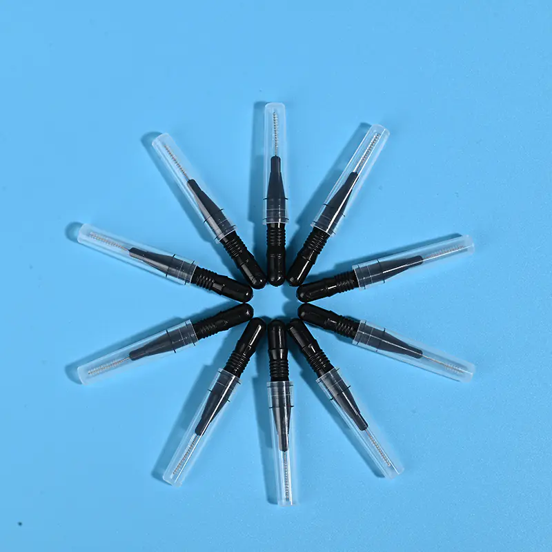 Nine black disposable interdental brushes with transparent protective caps arranged radially on light blue background
