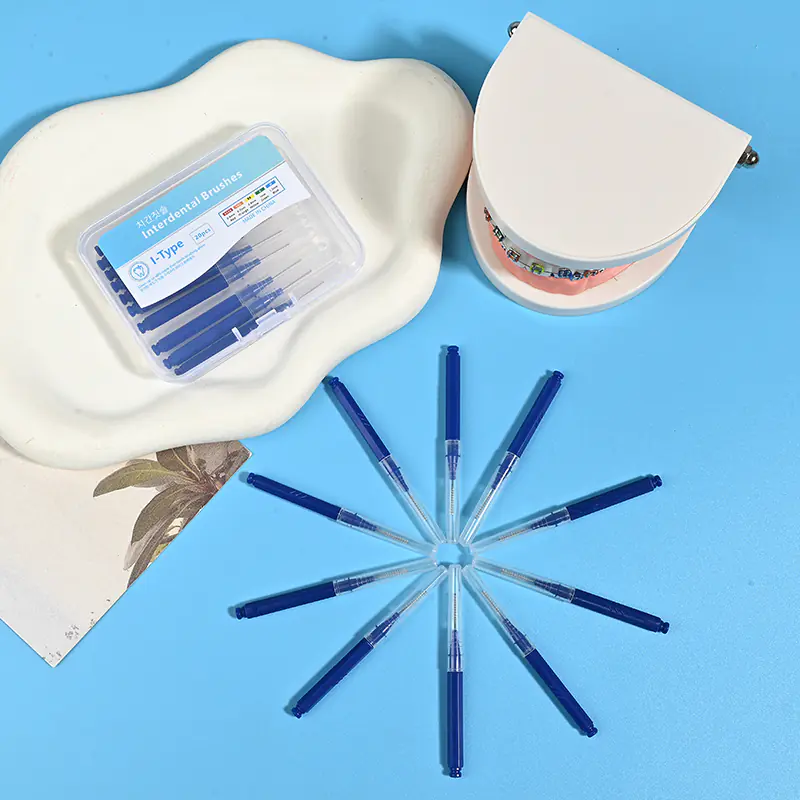 Dark blue straight I-type interdental cleaners arranged radial star shape with clear plastic storage box and orthodontic bracket dental model on beige irregular pad and bright blue background