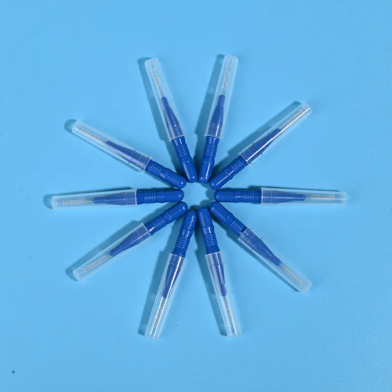 Nine dark blue disposable interdental brushes with transparent protective caps arranged radially on light blue background