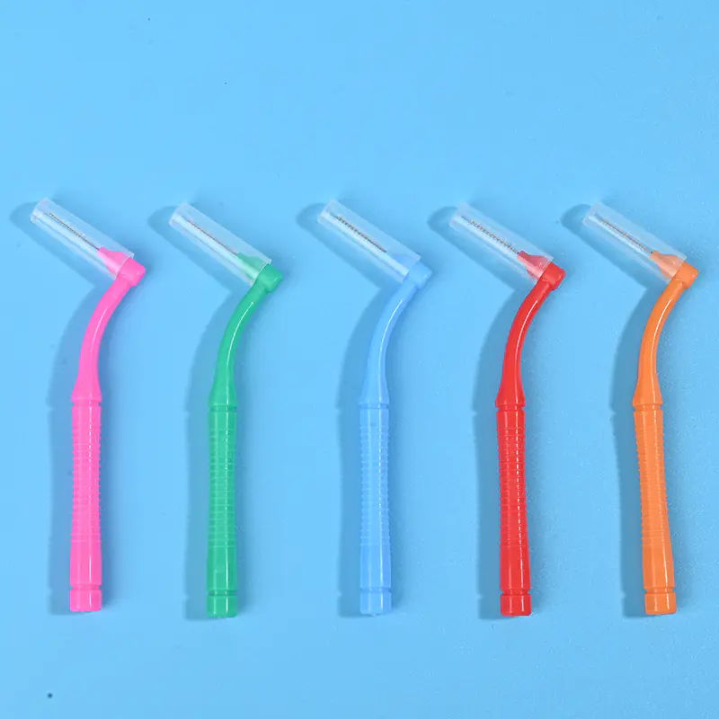 Five colorful L-shaped interdental brushes with protective caps arranged horizontally on light blue background, wholesale bend handle dental cleaning tools from Qingdao factory