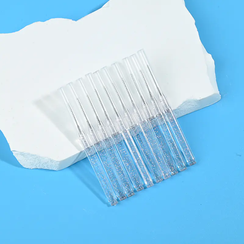 Glitter transparent retractable I-type interdental brushes placed slantwise beside irregular white stone on bright blue background