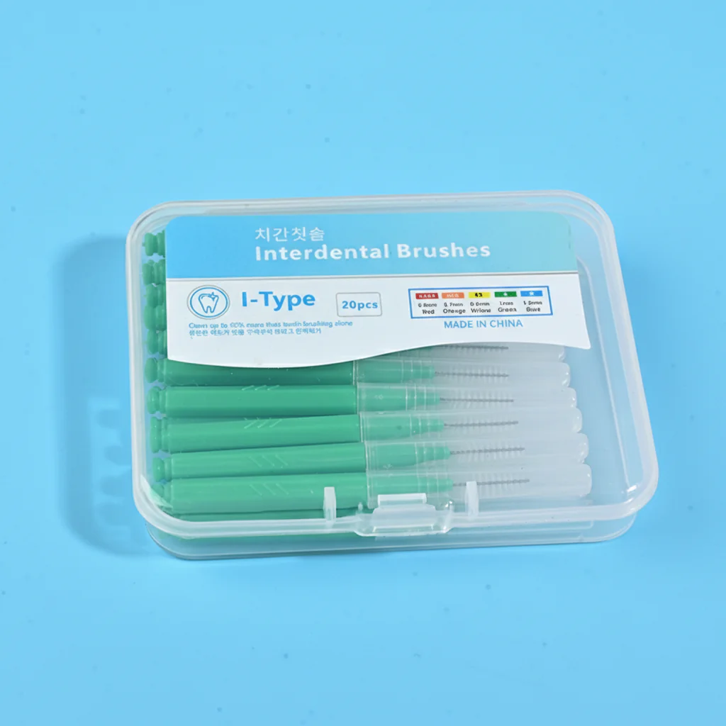 Close-up transparent plastic box filled with green straight I-type interdental brushes, bilingual Korean English label with full ISO size color specification chart on solid light blue background
