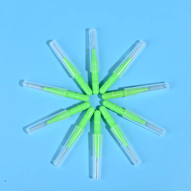 Nine green disposable interdental brushes with transparent protective caps arranged radially on light blue background