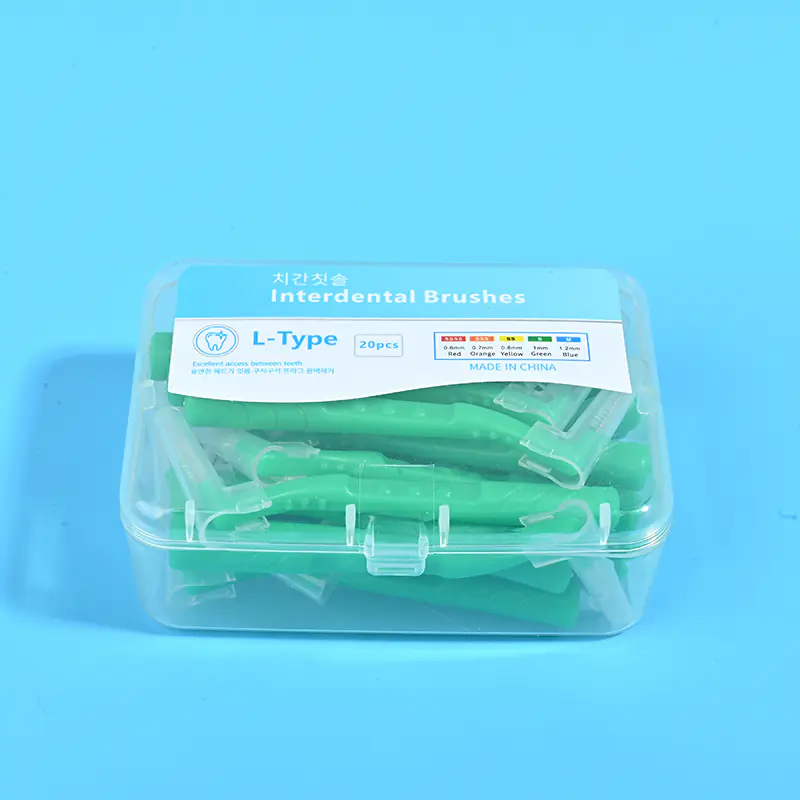 Close-up transparent plastic box filled with green L-type interdental brushes, bilingual Korean English label with full ISO size color specification chart on solid light blue background