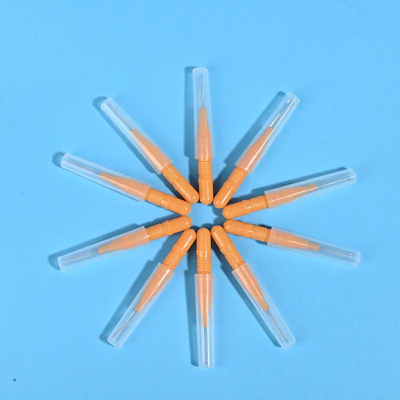 Nine orange disposable interdental brushes with transparent protective caps arranged radially on light blue background