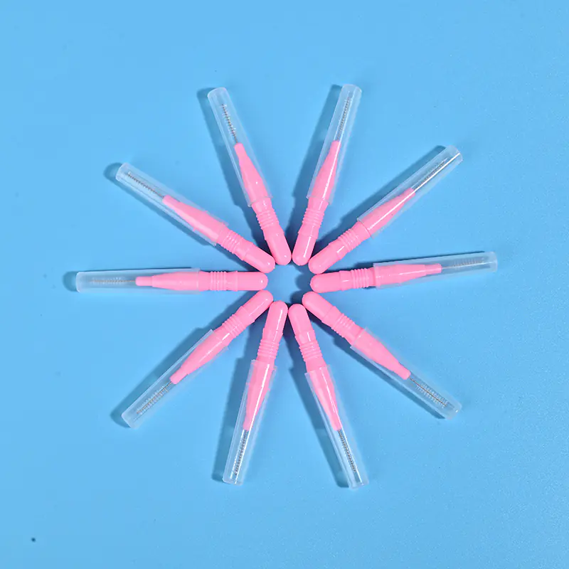 Nine pink disposable interdental brushes with transparent protective caps arranged radially on light blue background