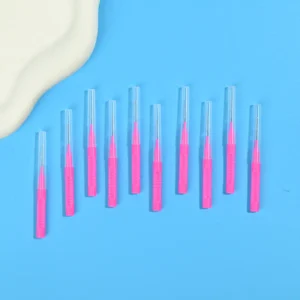 Pink retractable I-type interdental brushes arranged in oblique row beside irregular beige pad on solid light blue background