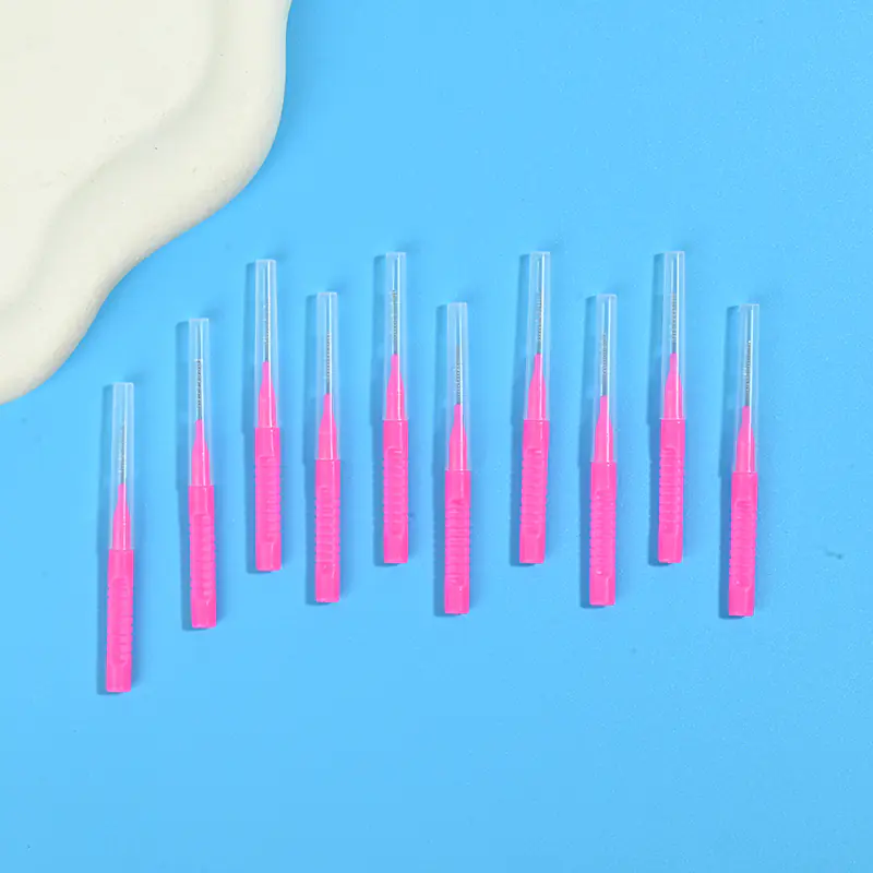 Pink retractable I-type interdental brushes arranged in oblique row beside irregular beige pad on solid light blue background