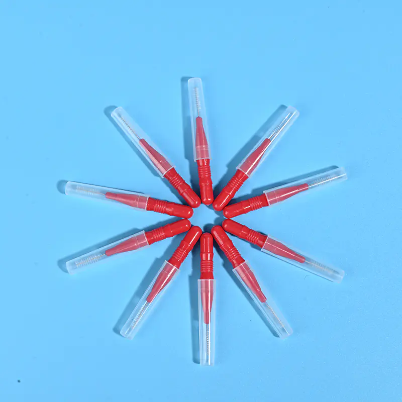 Nine red interdental brushes with transparent protective caps arranged radially on light blue background