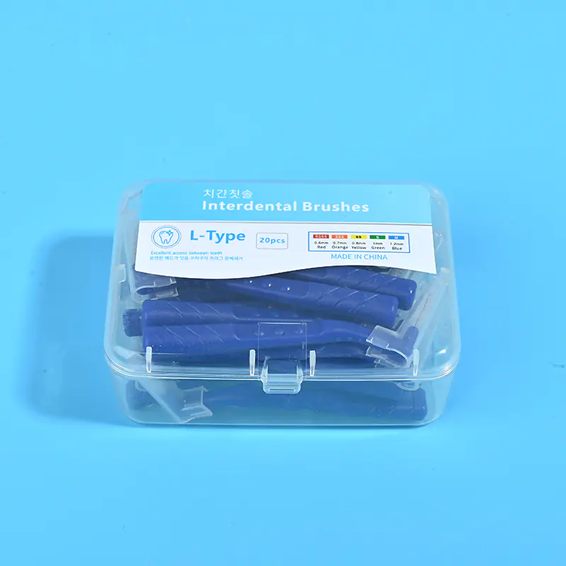 2-dark-blue-l-type-interdental-brush-20pcs-clear-box-closeup-blue-bg.jpg Close-up transparent plastic box filled with dark blue L-type interdental brushes, bilingual Korean English label with full ISO size chart on solid blue background