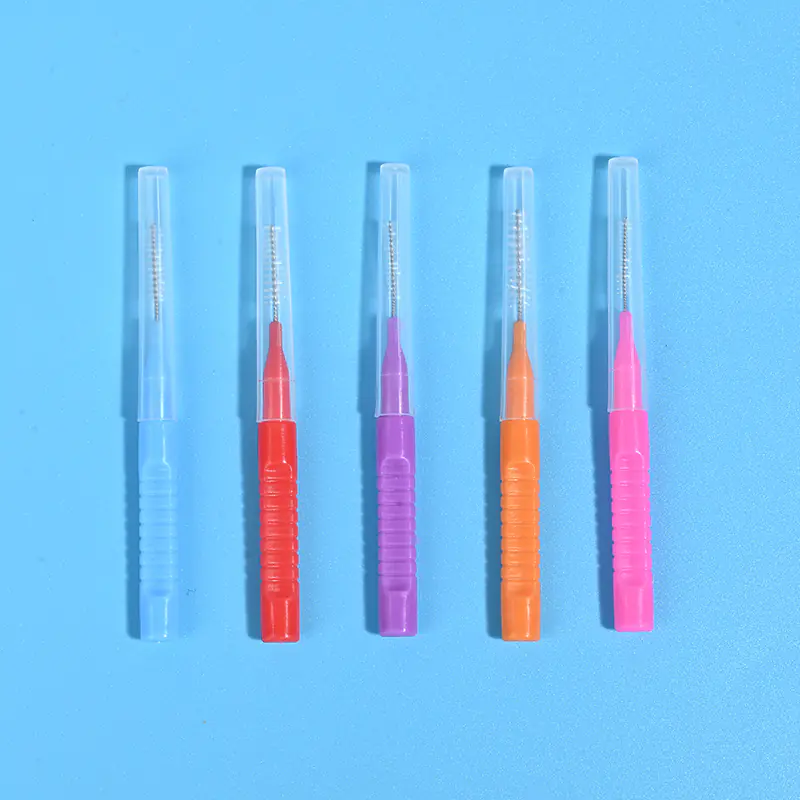 Five assorted color retractable I-type interdental brushes with transparent protective dust cap lined in a row on plain white background