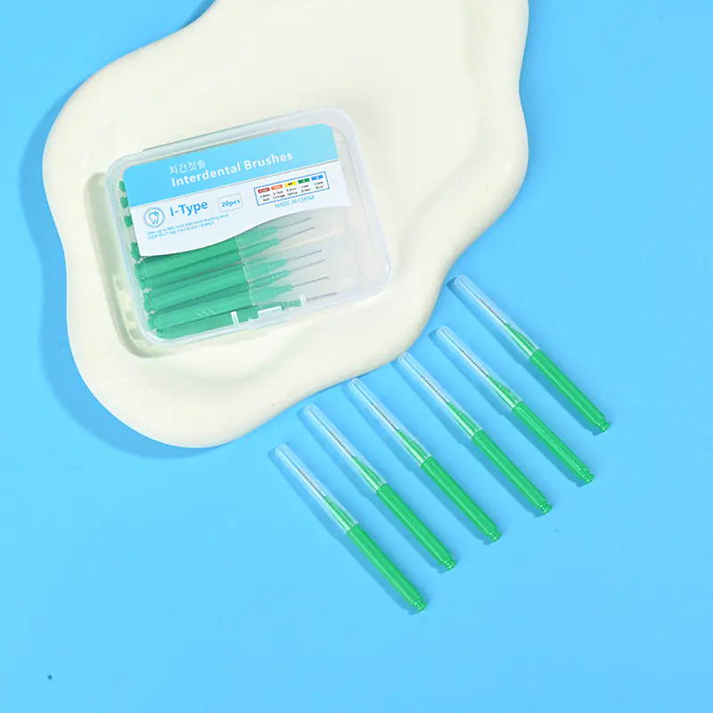 Green straight I-type interdental brushes laid side by side next to clear plastic storage box on irregular beige pad and bright blue background