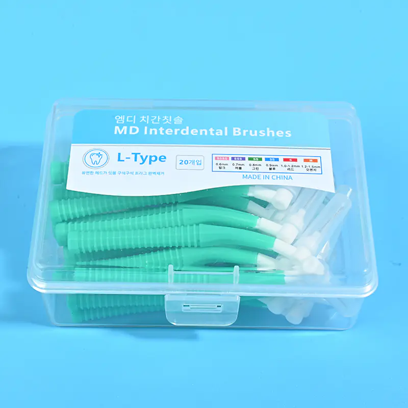 2-green-l-type-md-interdental-brush-20pcs-clear-box-closeup-blue-bg.jpg Close-up of transparent plastic box filled with green L-type MD interdental brushes, bilingual Korean English label with full ISO size chart on solid blue background
