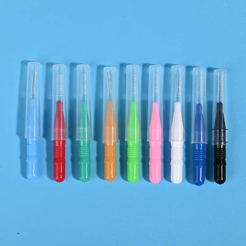 Nine different colored interdental brushes with protective caps lined up horizontally on blue background