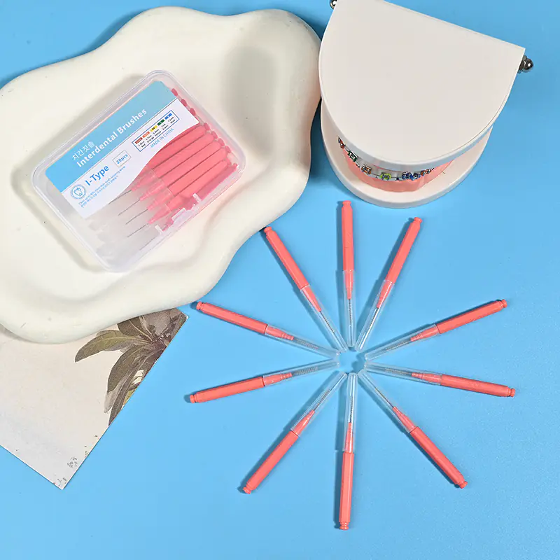 Close-up transparent plastic box filled with pink straight I-type interdental brushes, bilingual Korean English label with full ISO size color chart on solid light blue background