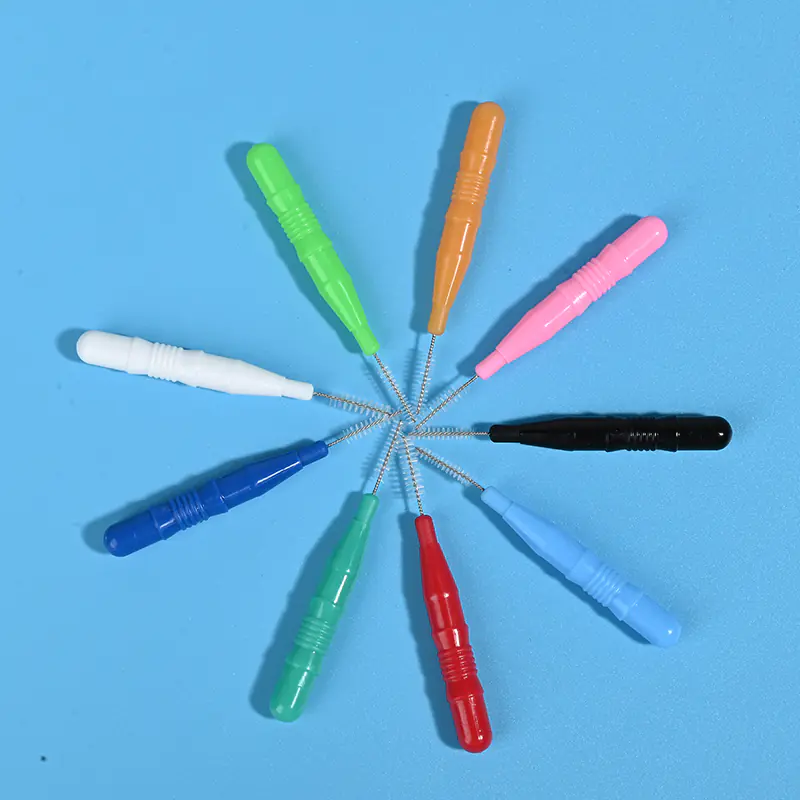 3-multi-color-interdental-brush-radial-layout-no-cap-blue-background.jpg Assorted colored interdental brushes without protective caps arranged radially on light blue background