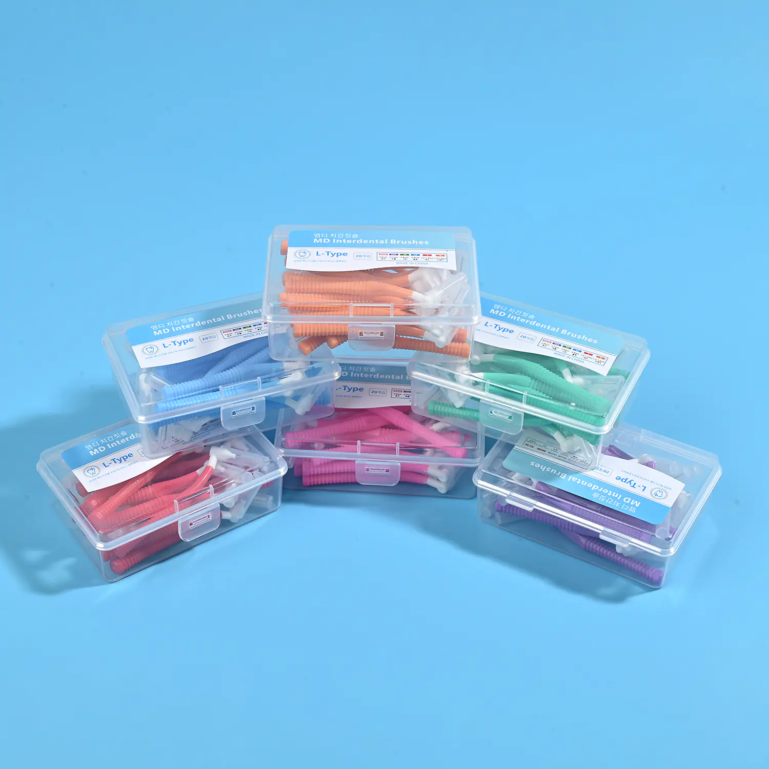 Stacked assorted multi-color L-type MD interdental brush boxes in orange blue green pink red purple on solid blue background