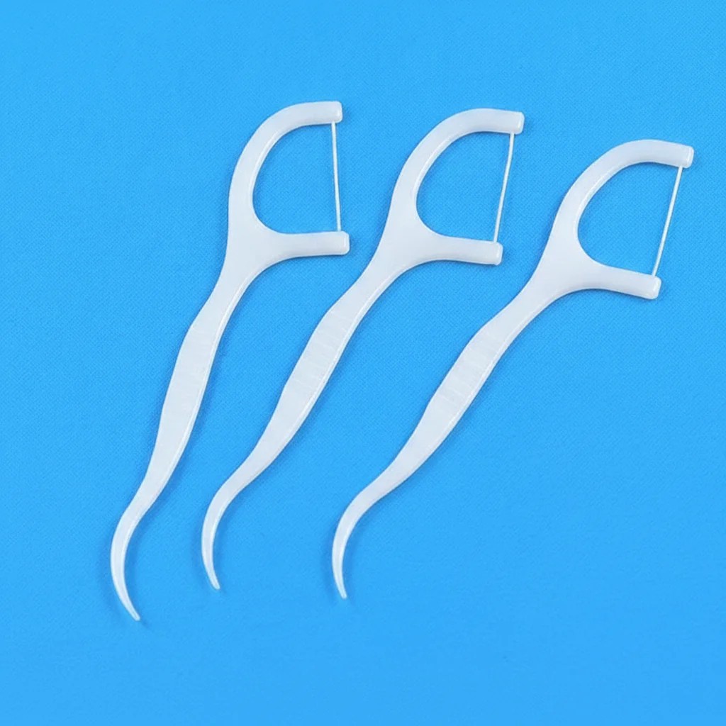 Three white disposable dental floss picks with curved tail hook, portable interdental floss cleaners